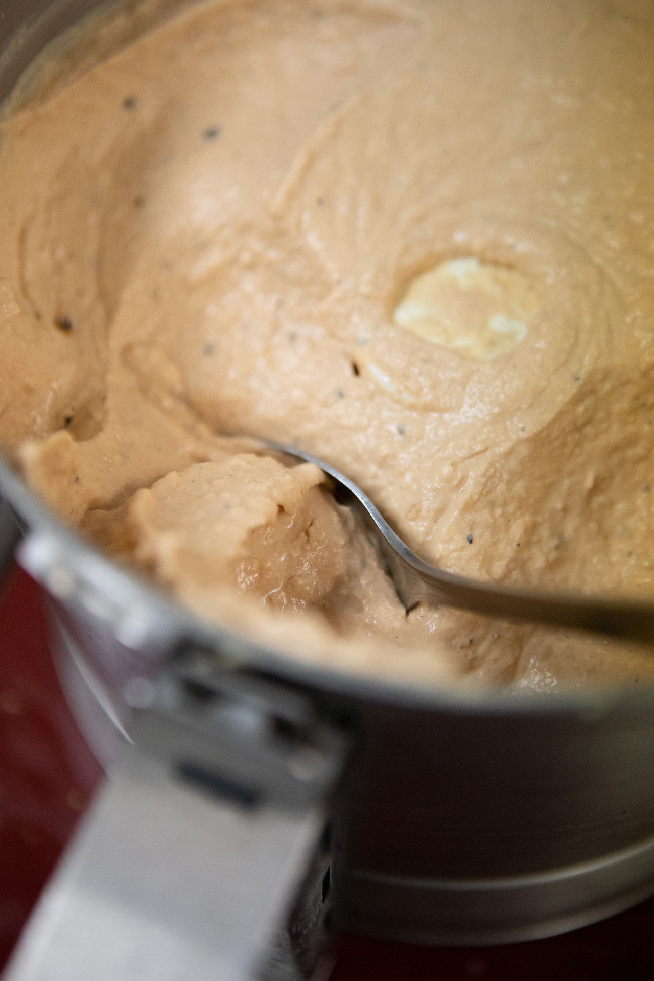 Silky smooth Roasted Tomato Habanero Hummus is pictured up close in a large metallic container.