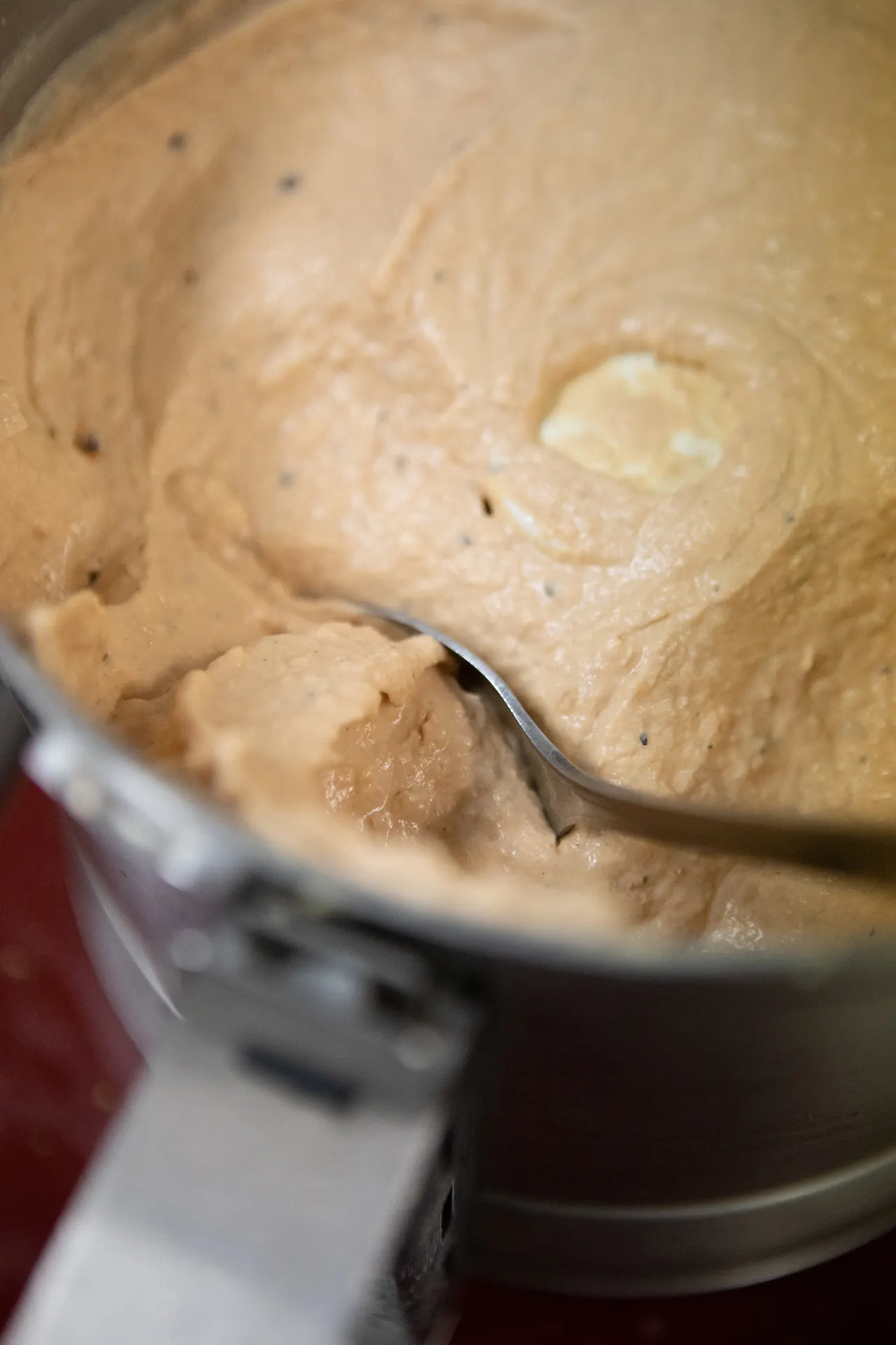 Silky smooth Roasted Tomato Habanero Hummus is presented up close in a large metallic container.