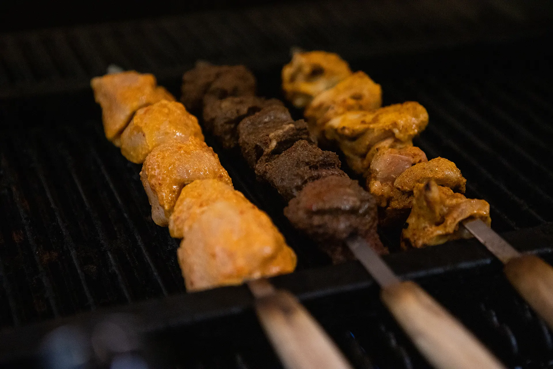 One white meat Chicken Kabob skewer, One dark meat Chicken Kabob skewer, and one Filet Mignon skewer are placed on the grill in the hummus labs kitchen.